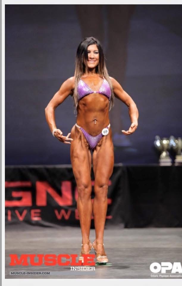 Dawn posing on stage at a figure competition
